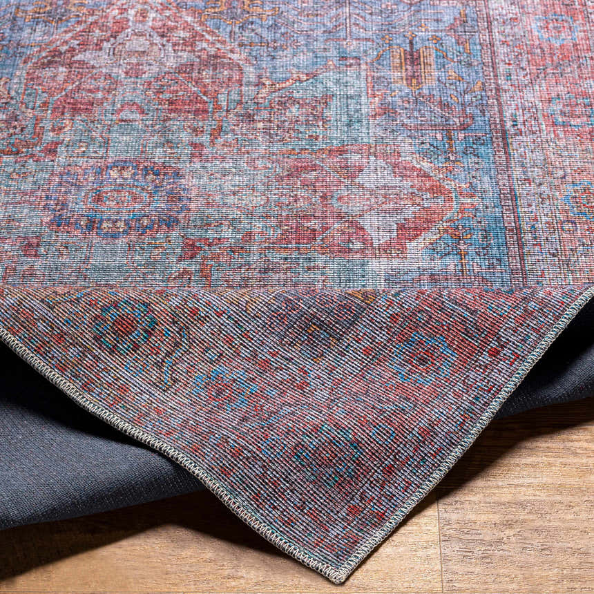 Close-up of the Otaki Washable Area Rug showing its traditional oriental pattern and colors: dark gray, purple, brown, and natural gray. Fold