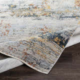 Close-up of the Ottawa Luxe Rug showing its cream, gray, blue, and tan abstract design and polyester texture. Fold
