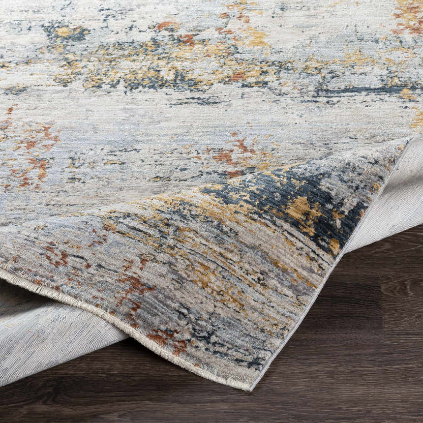 Close-up of the Ottawa Luxe Rug showing its cream, gray, blue, and tan abstract design and polyester texture. Fold