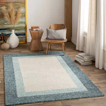 Living room scene with a Padada Green Bordered Cream Wool Rug, wood chair, side table, and neutral decor. Roomscene-Rectangle