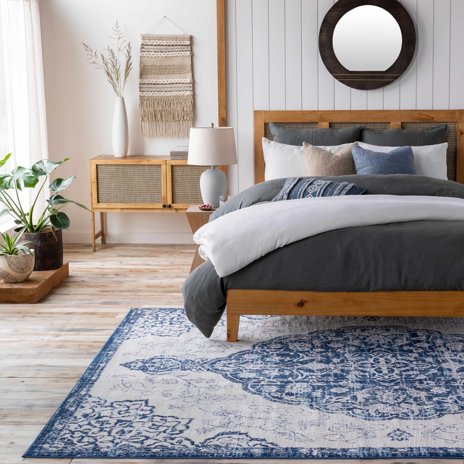 Bedroom scene with Pannal Area Rug in light beige and blue, wood bed frame, and neutral decor. Roomscene-Rectangle