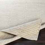 Close-up of the Partlow Area Rug, a beige and cream hand-knotted rug with a contemporary geometric pattern. Fold
