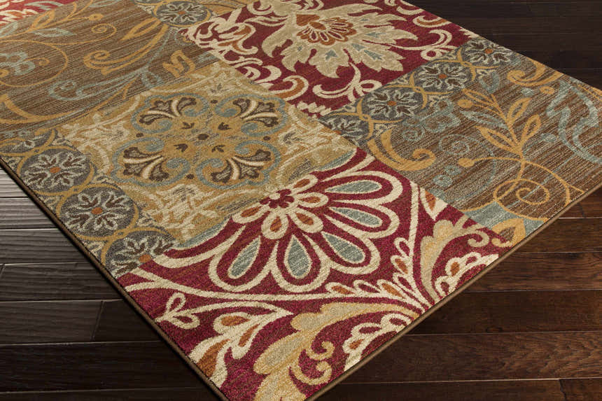 Close-up of the Pattersonville Area Rug featuring a patchwork of floral and geometric patterns in burgundy, brown, and tan. Corner