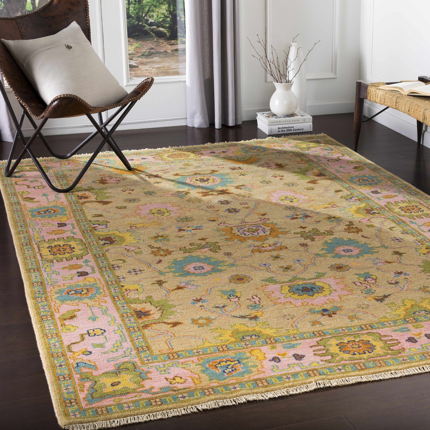 Living room scene with a Peacham Area Rug, leather chair, and natural light. The rug has brown, pink, and blue floral patterns. Roomscene-Rectangle