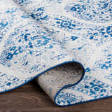 Close-up of the blue and off-white Penrhyndeudraeth Area Rug, showing the traditional pattern and machine-woven construction. Fold