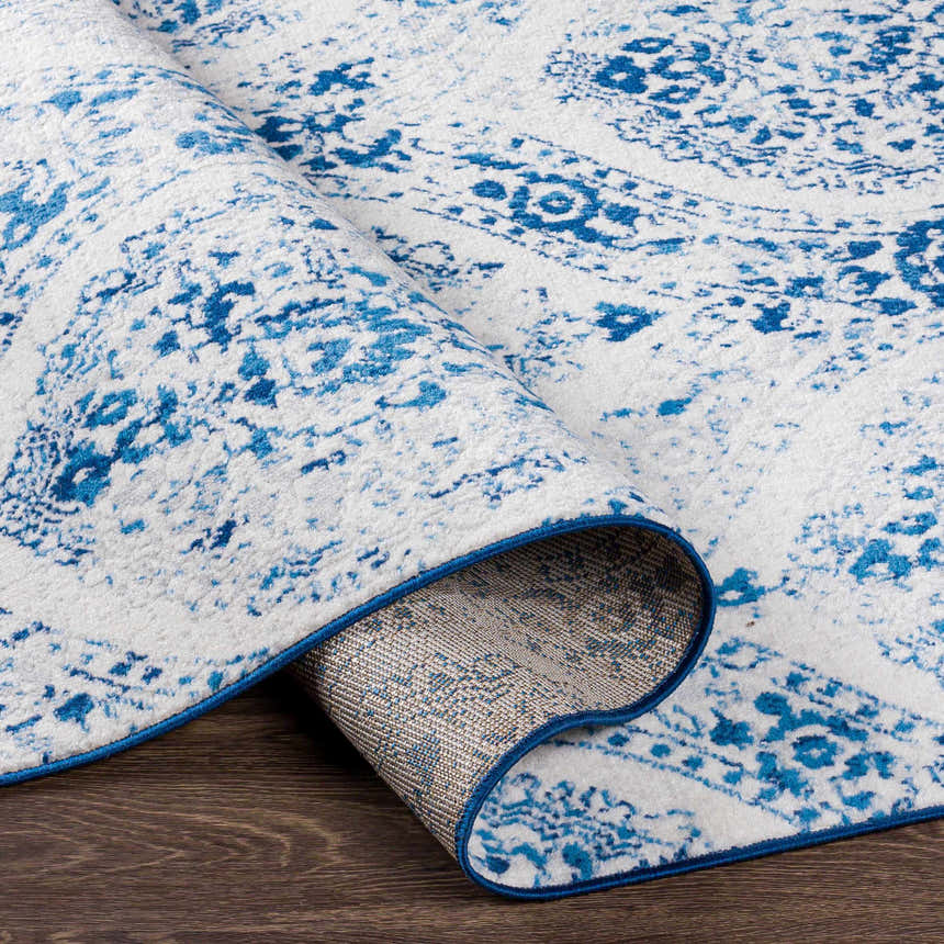 Close-up of the blue and off-white Penrhyndeudraeth Area Rug, showing the traditional pattern and machine-woven construction. Fold