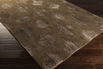 Close-up of the Pequea Area Carpet. Brown rug with abstract, distressed pattern on dark wood floors. Contemporary style. Corner