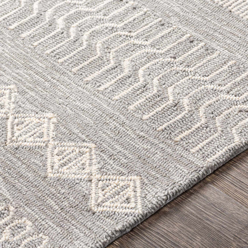 Close-up of the hand-hooked Pewsey Tribal Area Rug. Cream and gray geometric design on a textured polypropylene rug. Texture