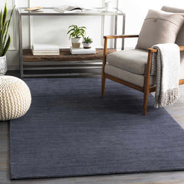 Living room scene with a dark blue Philipsburg Carpet, gray chair, and neutral decor. Roomscene-Rectangle