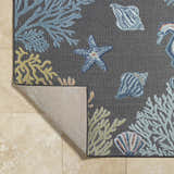 Close-up of Pasca Charcoal Area Rug with coastal design: blue coral, starfish, and shells on a charcoal background. Fold
