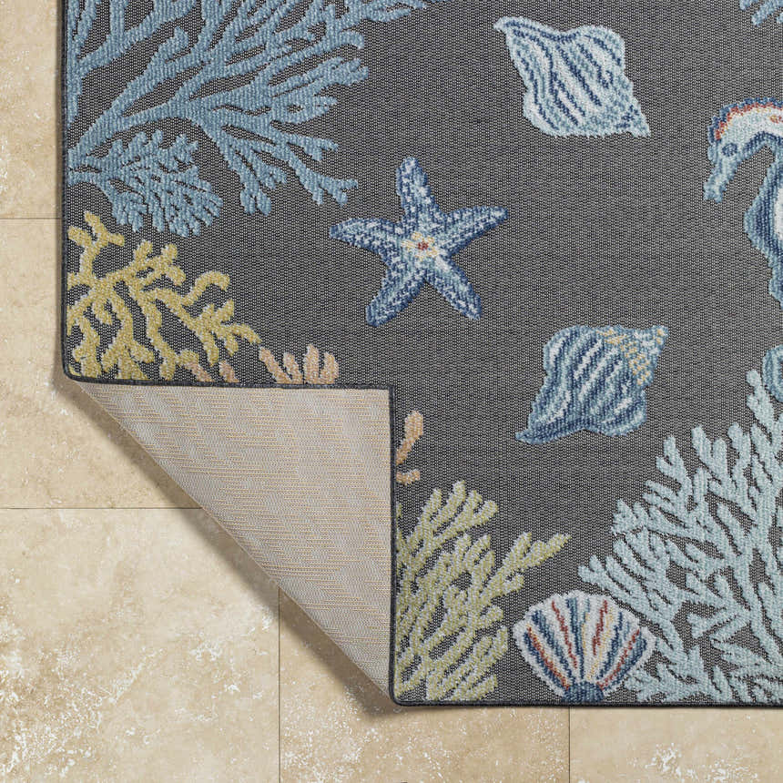 Close-up of Pasca Charcoal Area Rug with coastal design: blue coral, starfish, and shells on a charcoal background. Fold