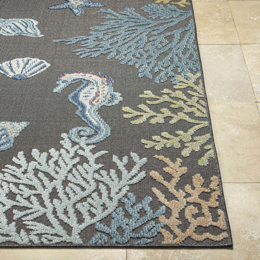 Close-up of Pasca Charcoal Area Rug showing coastal design with blue seahorse, starfish, shells, and coral on a charcoal background. Front