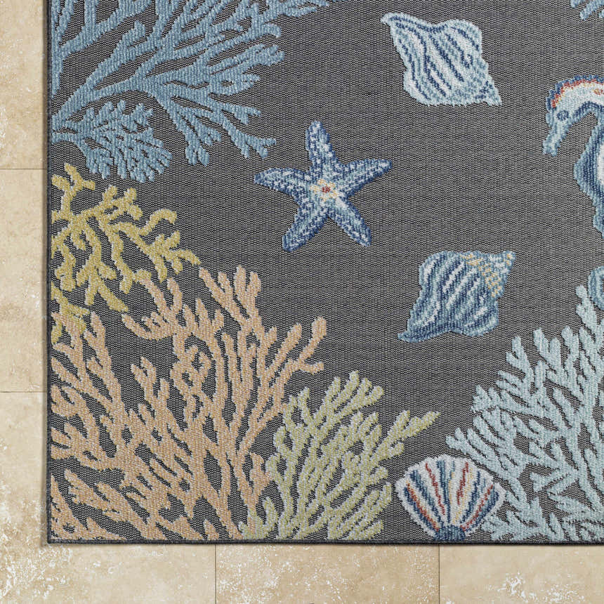 Close-up of Pasca Charcoal Area Rug showing coastal design with coral, starfish, and seashell patterns in blue, cream, mustard, and tan. Corner