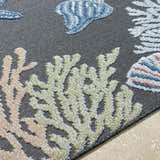 Close-up of Pasca Charcoal Area Rug with coastal design. Blue fish, olive coral, and tan coral on a charcoal background. Texture