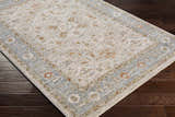 Close-up of the Phyllis Thick Luxe Statement Rug showing its beige, blue, and rust traditional pattern on dark wood floors. Corner