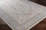Close-up of the Phyllis Thick Luxe Statement Rug, showcasing its light beige, blue, and brick red traditional pattern. Corner