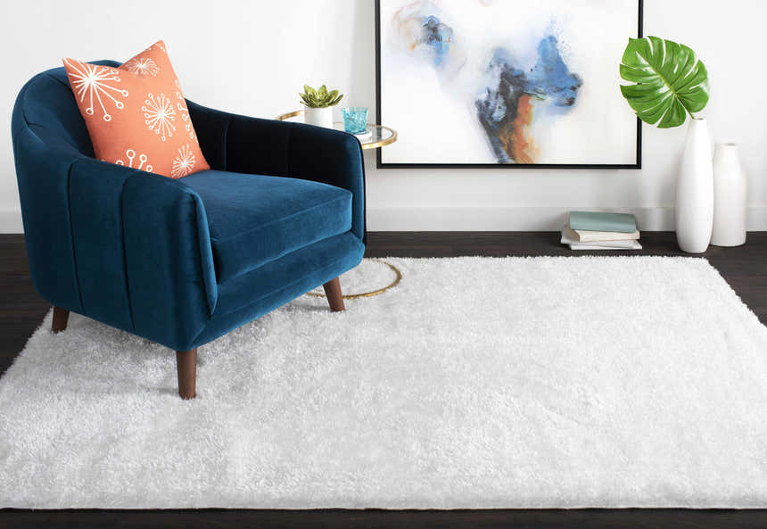 Living room scene with a white Piedmont Area Rug, blue accent chair, and abstract art. Roomscene-Rectangle