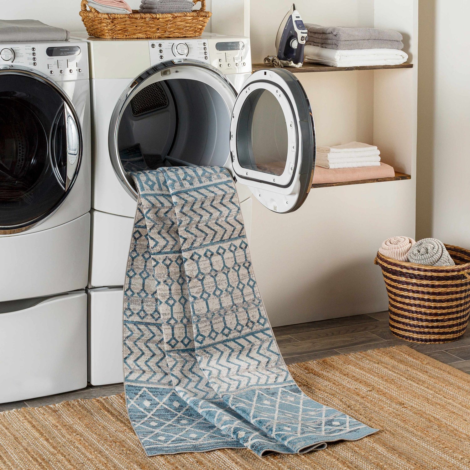 Laundry room scene with Pinamopoan Washable Area Rug in blue and gray coming out of the dryer. Jute rug underneath. Washing-Machine