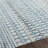 Close up of Pinamopoan Washable Area Rug featuring a light beige base with blue and gray geometric patterns. Texture