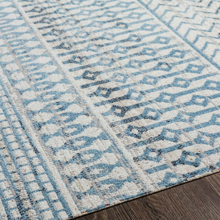 Close up of Pinamopoan Washable Area Rug featuring a light beige base with blue and gray geometric patterns. Texture