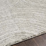 Close-up of the Pirton Luxe Rug. The rug has a textured, abstract pattern in cream, charcoal, and gray tones. Texture
