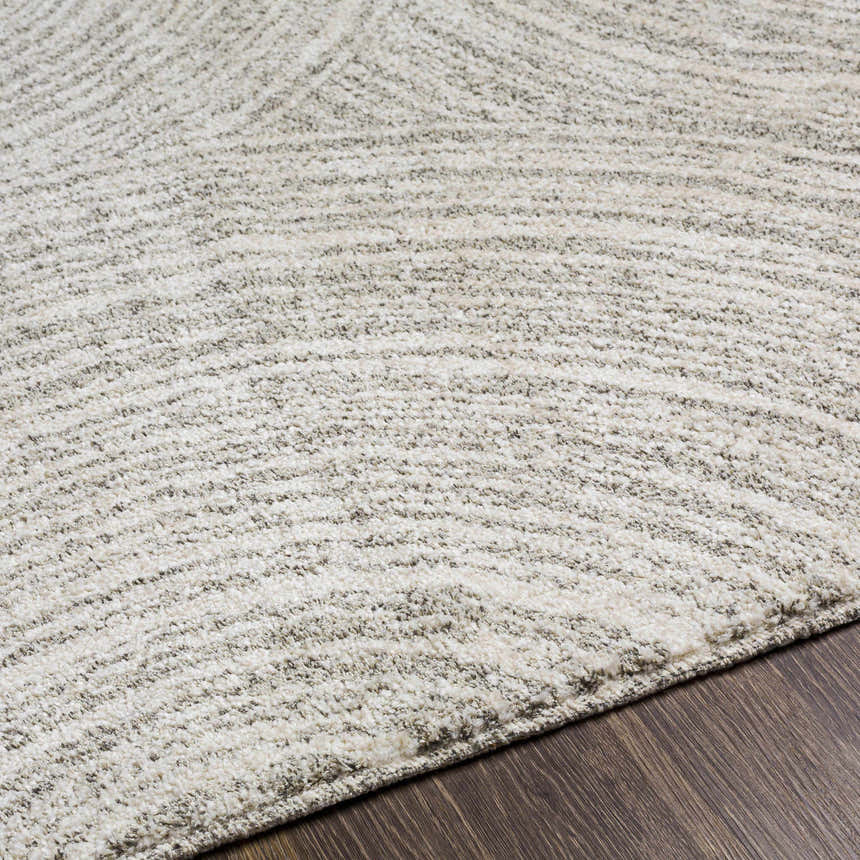Close-up of the Pirton Luxe Rug. The rug has a textured, abstract pattern in cream, charcoal, and gray tones. Texture
