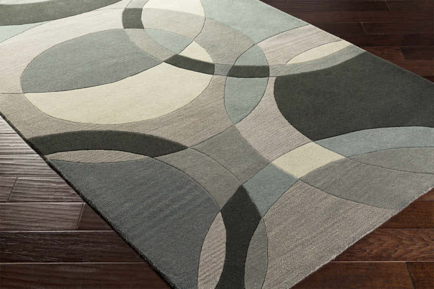 Close-up of the Rilton Gray Wool Carpet showing its geometric circle pattern and textures in gray, taupe, teal, and charcoal. Corner