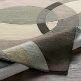 Close-up of the Rilton Gray Wool Carpet featuring a contemporary geometric pattern in shades of gray, charcoal, taupe, and teal. Fold