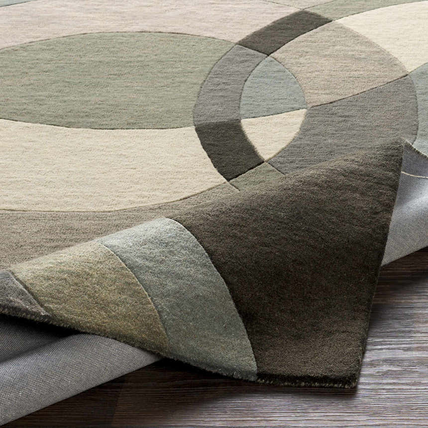 Close-up of the Rilton Gray Wool Carpet featuring a contemporary geometric pattern in shades of gray, charcoal, taupe, and teal. Fold