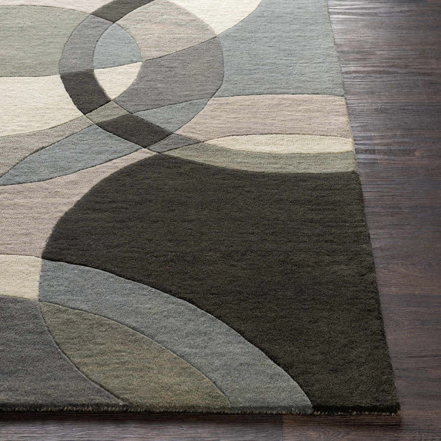 Close-up of the Rilton Gray Wool Carpet showing its geometric pattern, gray, black, taupe, and teal colors, and wool texture. Front