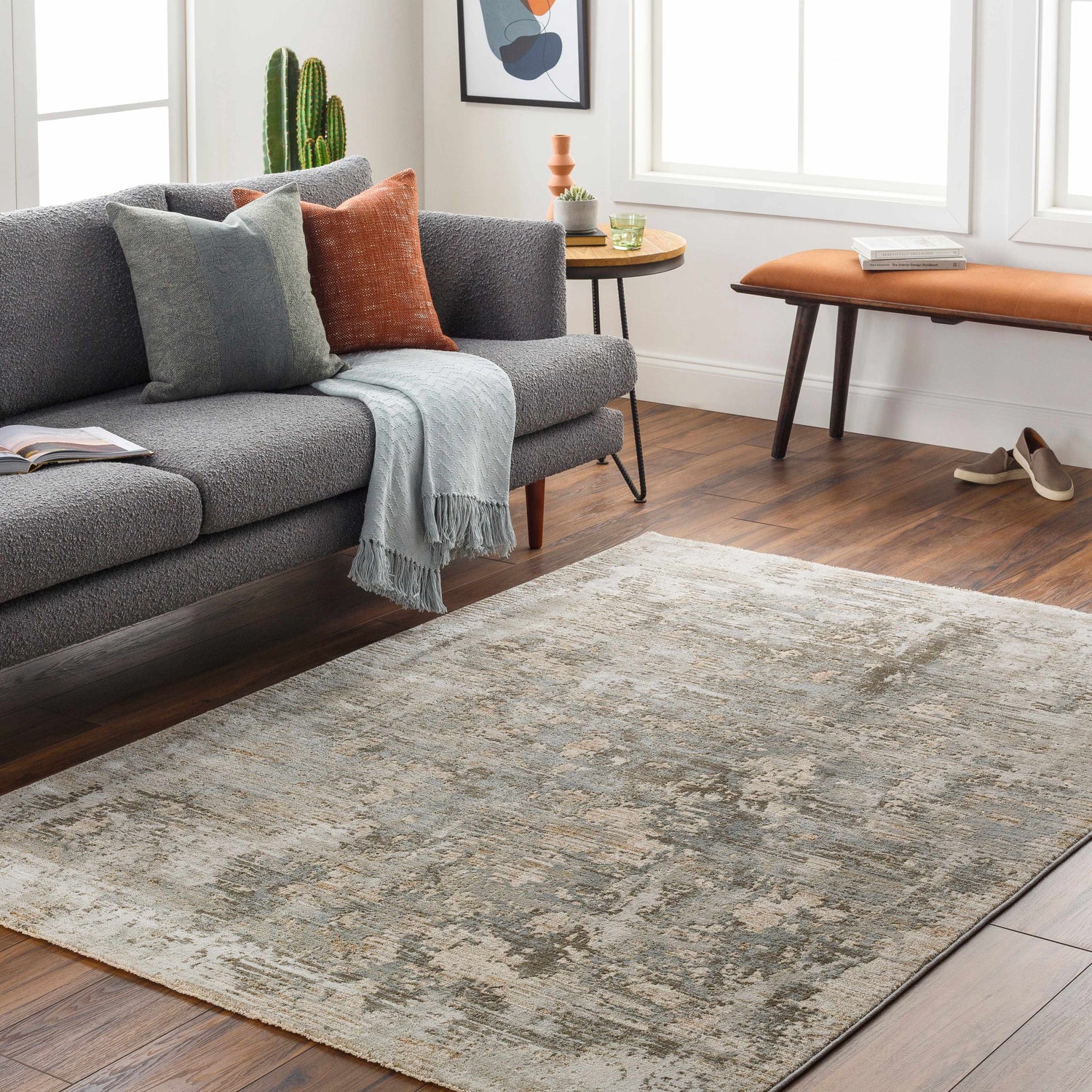 Living room scene with a gray sofa and Palanit Thick Luxe Boutique Rug in light beige, gray, and olive tones on a wood floor. Roomscene-Rectangle
