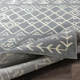 Close-up of the Plumsteadville Area Rug showing a slate gray and cream geometric pattern and machine-woven texture. Fold