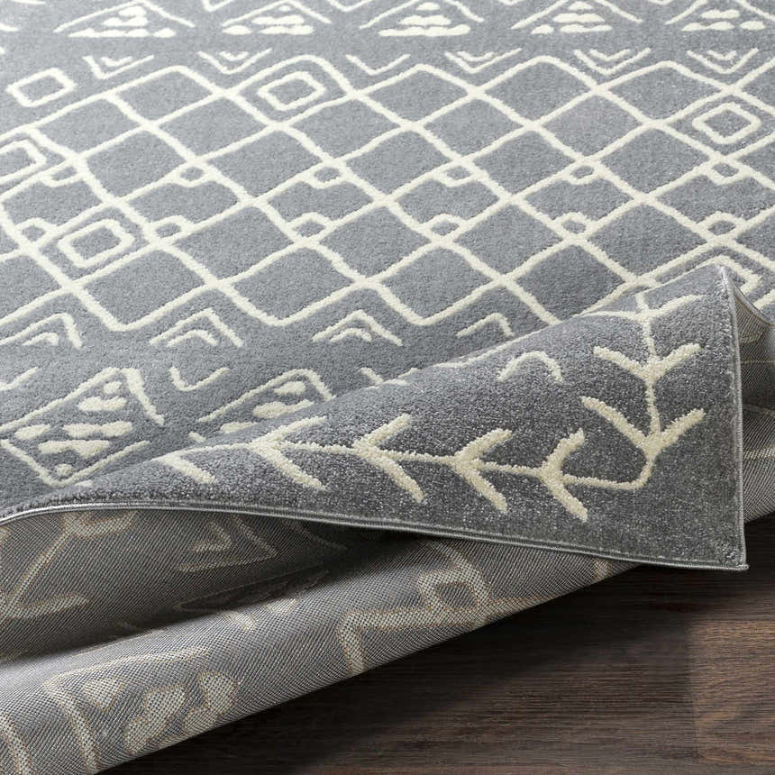 Close-up of the Plumsteadville Area Rug showing a slate gray and cream geometric pattern and machine-woven texture. Fold