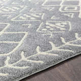Close-up of the Plumsteadville Area Rug. Cream geometric pattern on slate gray, machine-woven polypropylene. Farmhouse style. Texture