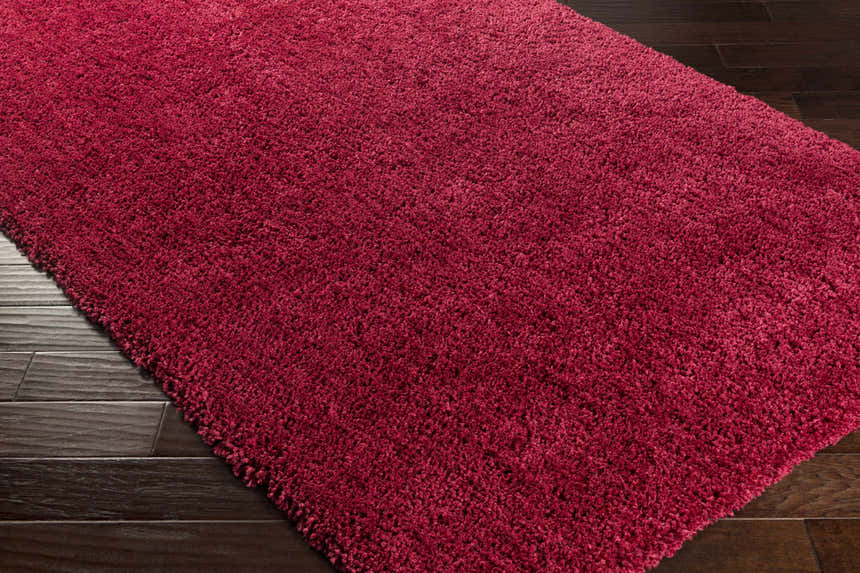 Close up of the dark red Porter Area Rug, a hand woven shag rug with a soft texture. Corner