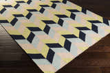 Close-up of the hand woven Pojoaque Area Carpet. Features a geometric design in dark blue, dusty pink, and light olive hues. Corner