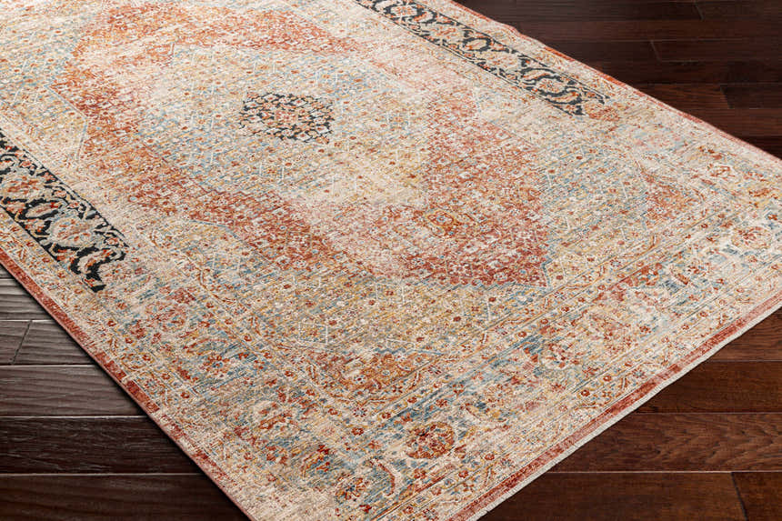 Close-up of the Polomolok Luxe Performance Rug. Traditional oriental design in brick red, cream, blue, and black on dark wood floor. Corner