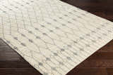 Close-up of ivory Pooleville Area Rug with a medium gray geometric pattern on dark wood floors. Corner
