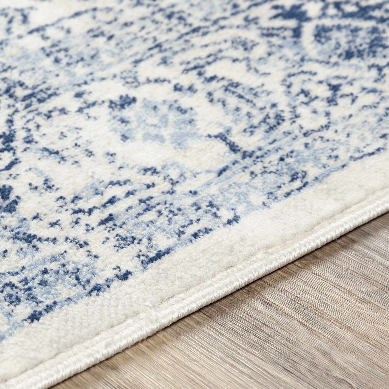 Close-up of the Pooraka Area Rug showing its soft texture and blue and off-white bohemian-inspired pattern. Texture