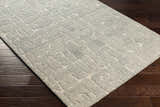 Close-up of the hand-tufted Posof Area Rug. Light beige and gray wool rug with a contemporary geometric pattern. Corner