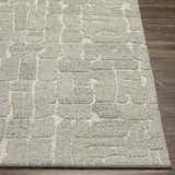 Close-up of the Posof Area Rug, a hand-tufted wool rug with a light gray geometric pattern on a light beige background. Front