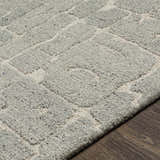 Close-up of the hand-tufted Posof Area Rug. Light gray and beige wool rug with a contemporary geometric pattern and textured pile. Texture