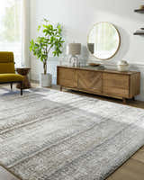 Living room scene with a cloud gray Prees Area Rug, wood console table, round mirror, and chartreuse accent chair. Roomscene-Rectangle