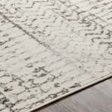Close-up of the Priston Area Rug showing its off-white base with black, charcoal, and gray abstract pattern. Texture