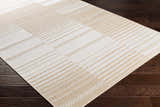 Close-up of the Portscatho Carpet - Clearance. Beige and light beige rug with a geometric striped pattern on dark wood floors. Corner