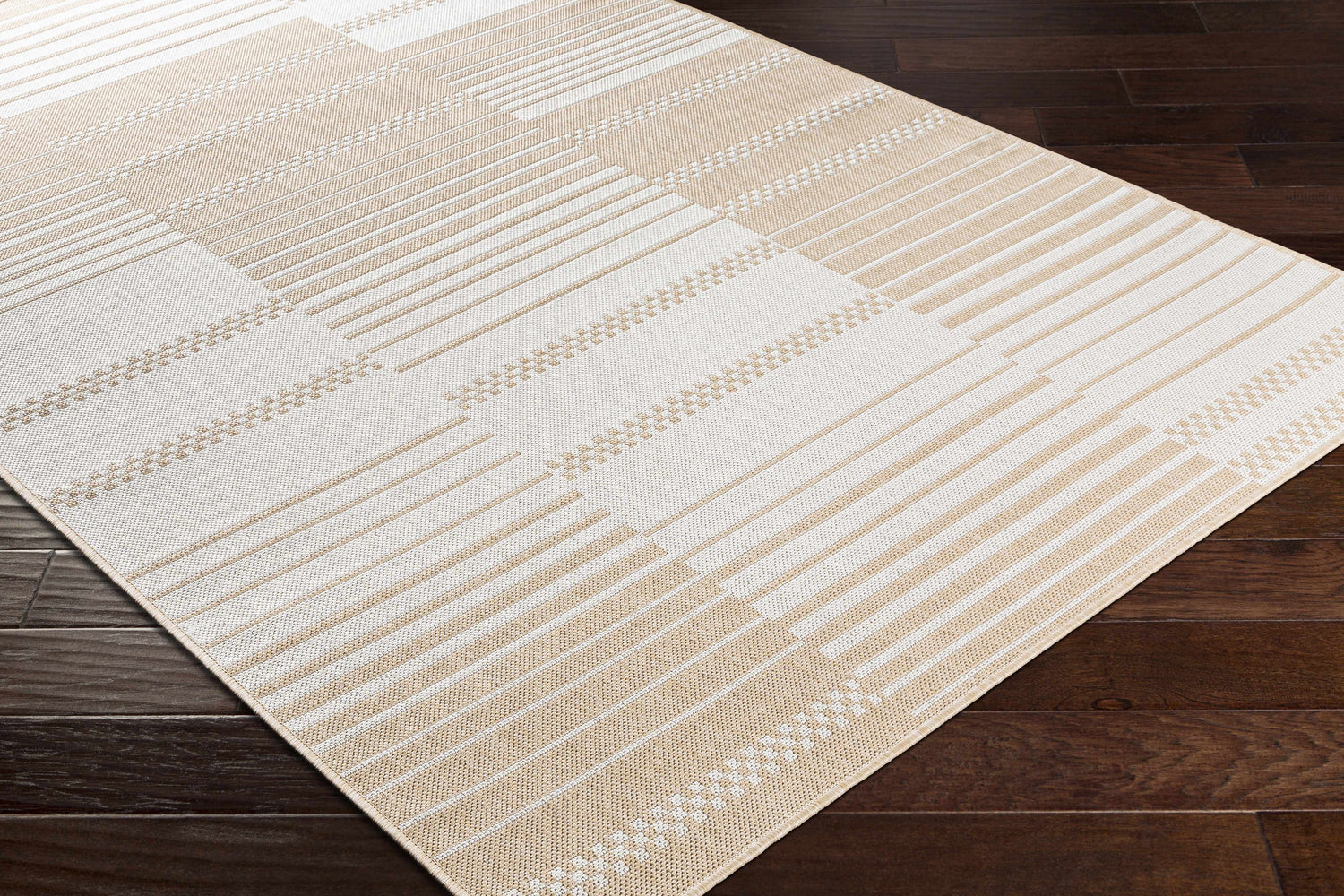 Close-up of the Portscatho Carpet - Clearance. Beige and light beige rug with a geometric striped pattern on dark wood floors. Corner