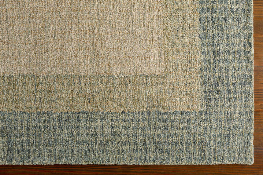 Close up of the hand-tufted Pualas Area Rug showing cream, sage, and light beige stripes and wool texture. Corner