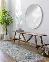 Entryway with a blue Pukwana Area Rug runner, wood bench, round mirror, and potted plant. Roomscene-Runner