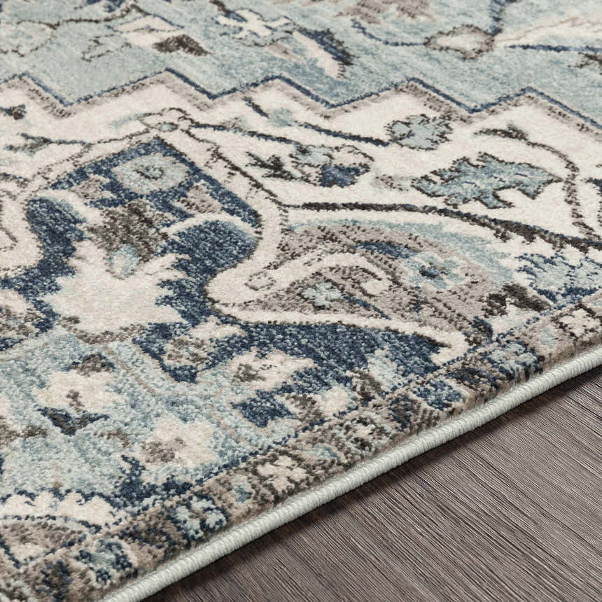 Close-up of the Pukwana Area Rug, showcasing its traditional, bohemian pattern in shades of blue, gray, and oatmeal. Texture