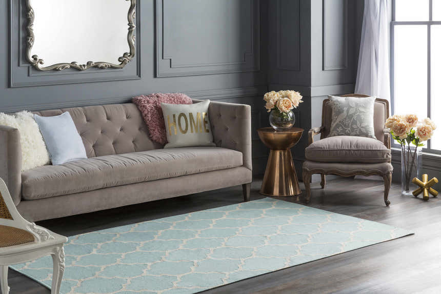 Living room scene with a Ragan Ice Blue Trellis Cotton Rug, gray walls, and a tufted sofa with decorative pillows. Roomscene-Rectangle